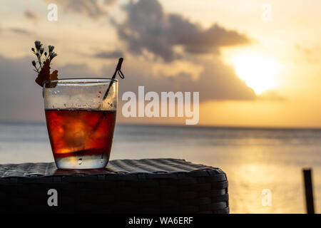 Un iced summer cocktail isolato nella parte anteriore di un tramonto sul mare Foto Stock