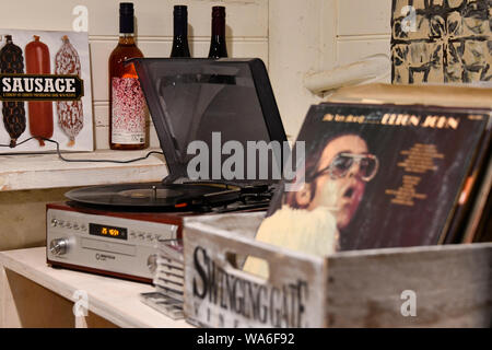 Dischi in Vinile & Record Giocatore con salsiccia Prenota e bottiglie di vino e arte appesa sul muro, porta basculante cantina porta Cantina Launceston, Australia Foto Stock