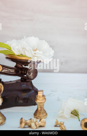 Antique vintage scala di misurazione con pesi con freschi tè bianco rose fiori sul bianco sullo sfondo di legno. La natura degli ingredienti. Pura e simpiity concep Foto Stock