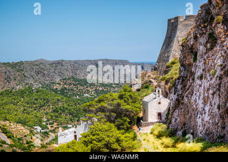 Bellissima greca paesaggio di montagna con una piccola chiesa bianca a lato della scogliera del castello iconico a Chora, Kythira Island, Grecia. Foto Stock