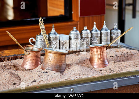 Tradizionale caffè turco cotte nella calda sabbia e tre cezve in rame Foto Stock
