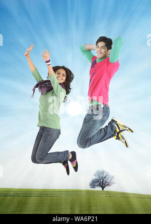 Giovane coppia che salta in aria e sorride Foto Stock