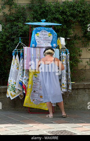 Donna vendita di souvenir asciugamani su un mercato in stallo al di fuori di Sorrento, Italia Foto Stock