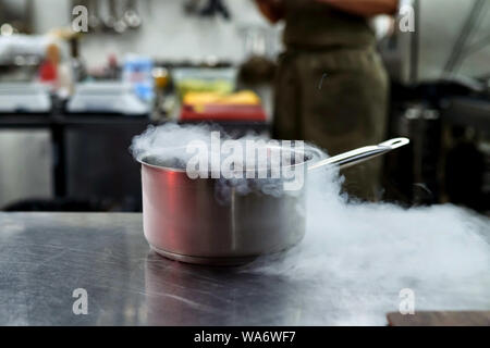 Azoto liquido in una padella. La cottura. Il vapore. Cuocere. Contro lo sfondo. Tutto ciò che accade in cucina. Foto Stock