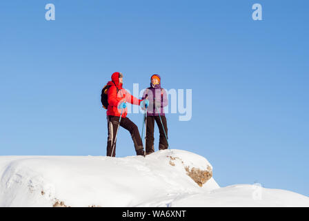 L uomo e la donna gli escursionisti sulla cima di una collina innevate su un gelido inverno giornata contro il cielo Foto Stock
