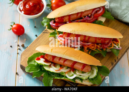 Tradizionale american fast food. Barbecue grigliate di hot dog con verdure fresche su un tavolo di legno. Foto Stock