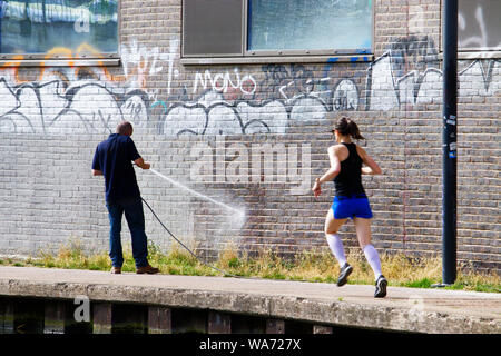 Un operaio rimuove graffiti da una parete dal Regents Canal a Londra Foto Stock