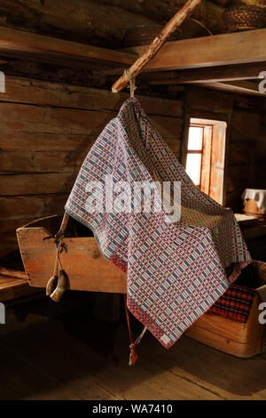 Frammento della parte interna di un vecchio contadino log cabin con una culla Foto Stock