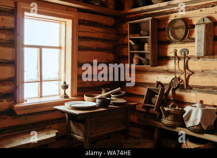 Frammento della parte interna di un vecchio contadino log cabin - una tabella con pavimenti in legno e piatti in ceramica, una lampada di kerosene Foto Stock