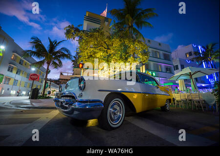 MIAMI - Gennaio 08, 2018: luci al neon decorano l'architettura Art Deco dietro un classico americano auto parcheggiate su Ocean Drive di South Beach. Foto Stock