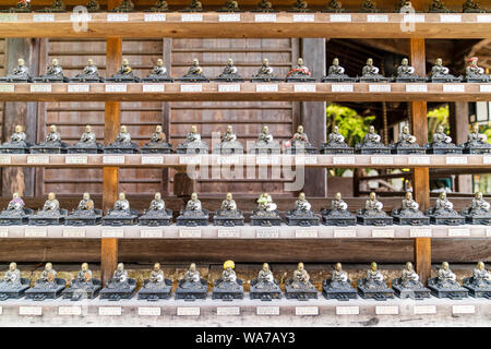 Giappone, Miyajima. Tempio Daisho-in. File di statue di Buddha seduto in miniatura disposte su piccoli scaffali in lunghe file, ciascuna figura ha il suo nome benefattori. Foto Stock