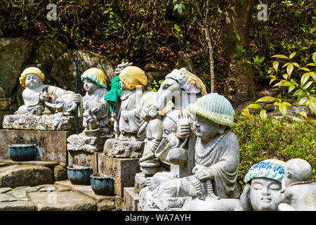 Giappone, Miyajima. Daisho-nel tempio. Fila di piccola pietra Jizo statue di monaci buddisti, tutti diversi. Tutti hanno lavorato a maglia cappelli di lana su Foto Stock