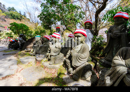 Giappone, Miyajima. Rakan piccole statue di monaci buddisti, discepoli di Shaka, rivestimento gradino di pietra percorso attraverso l'entrata del Daisho-nel tempio. Foto Stock