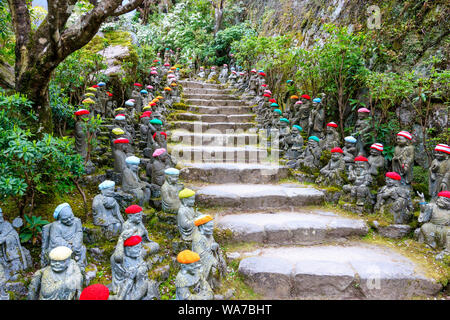 Giappone, Miyajima. Rakan piccole statue di monaci buddisti, discepoli di Shaka, rivestimento gradino di pietra percorso attraverso l'entrata del Daisho-nel tempio. Foto Stock