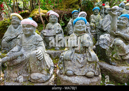 Giappone, Miyajima. Rakan piccole statue di monaci buddisti, discepoli di Shaka, rivestimento gradino di pietra percorso attraverso l'entrata del Daisho-nel tempio. Foto Stock