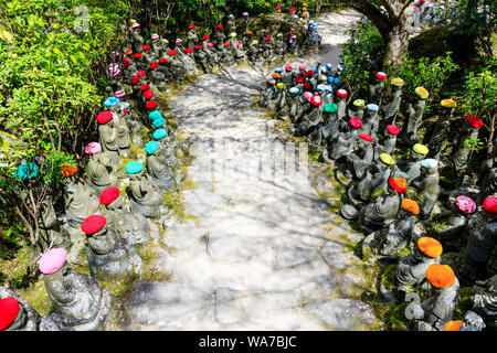 Giappone, Miyajima. Rakan piccole statue di monaci buddisti, discepoli di Shaka, rivestimento gradino di pietra percorso attraverso l'entrata del Daisho-nel tempio. Foto Stock