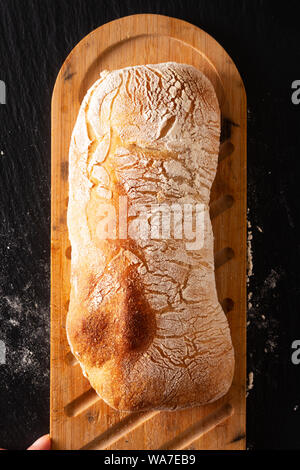 Concetto di cibo in casa artigianale di stile italiano classico pasta lievitata Ciabatta pane su ardesia nera con scheda spazio di copia Foto Stock