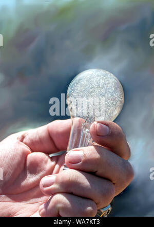 Una mano d'uomo detiene un vecchio, antichi lampadina con vetro crackled Foto Stock