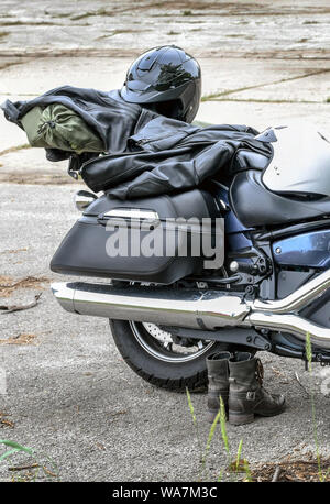 Una coppia di uomini stivali del resto lungo il lato di una motocicletta, tutti pronti per un viaggio su strada Foto Stock