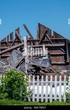 Un fienile in rovina dopo forti tempeste, ma un Picket Fence si erge ancora Foto Stock