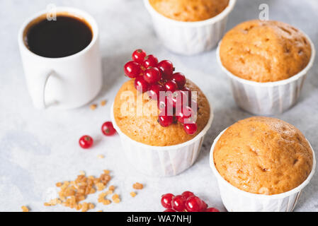 In casa dolce vaniglia muffin decorata con bacche rosse e la tazza di caffè nero caffè espresso Foto Stock