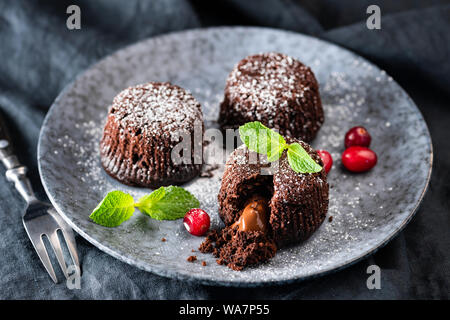 Torta di lava, nucleo fuso cioccolato fondente torta decorata con foglia di menta e mirtilli rossi Foto Stock