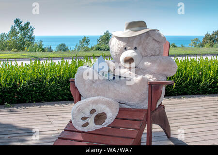 Recare in vacanza, si siede su una sedia a sdraio vicino al lago Foto Stock