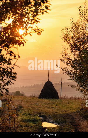 Autunno magnifico paesaggio di montagna dei Carpazi con pagliaio di sunrise Foto Stock
