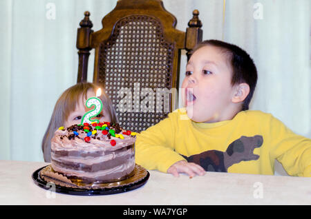 Little Boy soffiando fuori candele sulla sua sorella torta di compleanno Foto Stock