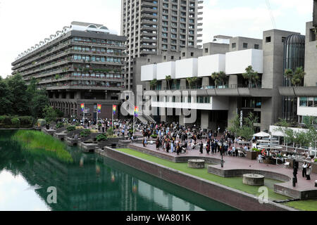 Cerimonie di laurea e gli studenti con le famiglie al di fuori del Barbican Centre & Barbican Estate appartamenti e il lago nella città di Londra UK KATHY DEWITT Foto Stock