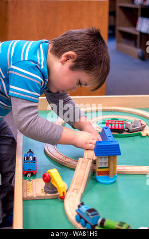 Little Boy giocando con i treni su un treno in legno tabella Foto Stock