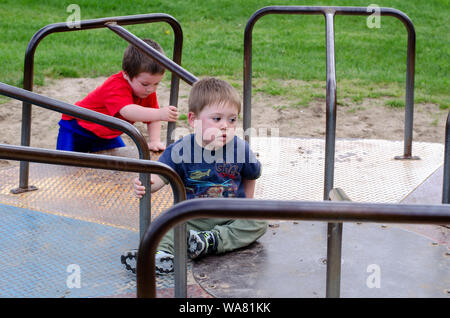 Ragazzi piccoli su un Merry Go Round, uno non è così sicuro che egli è come andare a questo! Foto Stock