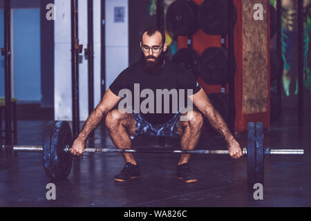 Giovane uomo barbuto fare sollevamento pesi nella palestra crossfit Foto Stock