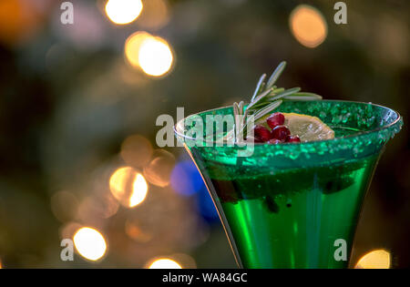 Green flute da champagne con rosmarino, semi di melograno e un rametto di calce galleggiante sul frizzante Foto Stock