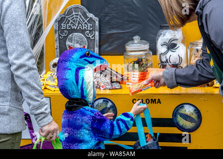 Ottobre 27, 2018 Coloma MI USA; un bambino in un costume di dinosauri accetta una caramella dolce trattare durante un dolcetto o scherzetto Halloween Foto Stock