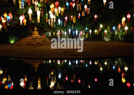 La zona del lago con seduta statua del Buddha sotto un albero Bodhi accanto al viharn del tempio Buddista Wat Phan Tao che è utilizzato dai monaci alla luce centinaia di lampade durante l annuale Loy Krathong festival. Chang, Wat Chiang Mai e Chiang Mai Provincia, Thailandia, Sud Est asiatico Foto Stock