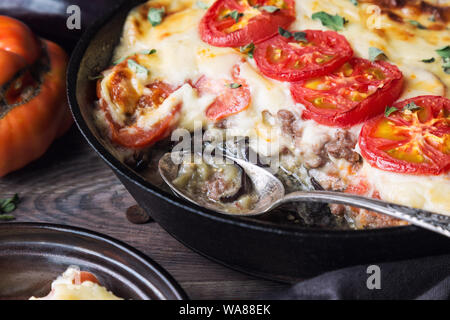 Freschi Fatti in casa La moussaka in padella di ferro su legno rustico sfondo con ingredienti. La cucina greca. Foto Stock