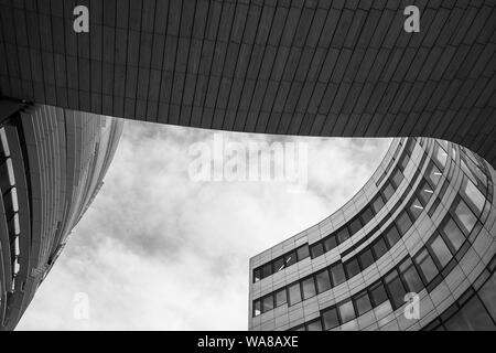Basso angolo di vista a plaza tra 2 edificio con curvatura forma libera forma del contorno. In bianco e nero di architettura astratta la facciata esterna. Foto Stock