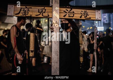 Un manifestante detiene una croce di legno con la scritta 'Devil governa Hong Kong" durante la dimostrazione.i manifestanti sono scesi in piazza in una piovosa domenica di un pro-democrazia dimostrazione sull isola di Hong Kong, chiedono il ritiro completo della legge in materia di estradizione e il governo per impostare un inchiesta indipendente sui recenti scontri tra manifestanti e forze di polizia - Gli organizzatori hanno dichiarato che questa è stata la più grande rally durante la settimana. Foto Stock