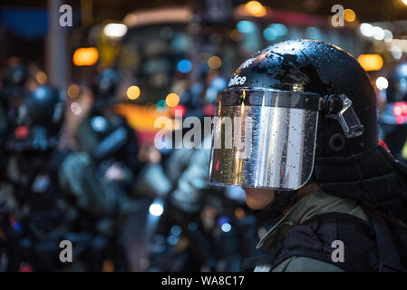 Un poliziotto sta di guardia in la pioggia durante una dimostrazione pacifica.i manifestanti hanno sfidato la polizia ordina e sfilato da Causeway Bay tutto il modo di Sheung Wan. Nonostante la pioggia pesante, oltre un milione di partecipanti hanno sfilato pacificamente a sostegno dell'anti-movimento di estradizione. Gli organizzatori stimano 1,7 milioni di persone hanno partecipato al rally mentre la polizia ha messo la figura al di sotto di 500.000. Foto Stock