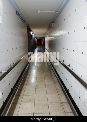 Immagine verticale di un corridoio bianco creepy dell'ospedale con un pavimenti e pareti in ceramica Foto Stock