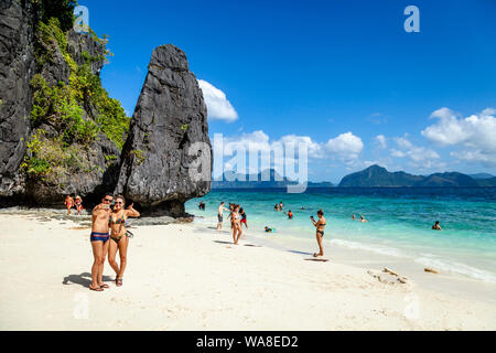 Giovani turisti posano per Foto sulla spiaggia Entalula, El Nido, PALAWAN FILIPPINE Foto Stock