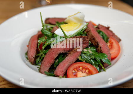 Arrosto di manzo starter con insalata di rucola e uova su piastra bianca Foto Stock