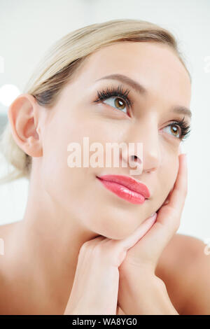 Ritratto di bella donna giovane con lunghe ciglia fantasticando e guardando in alto Foto Stock