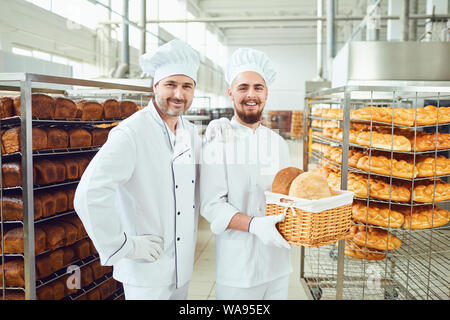 Fornai sullo sfondo di vassoi con vari tipi di pane in una panetteria. Foto Stock