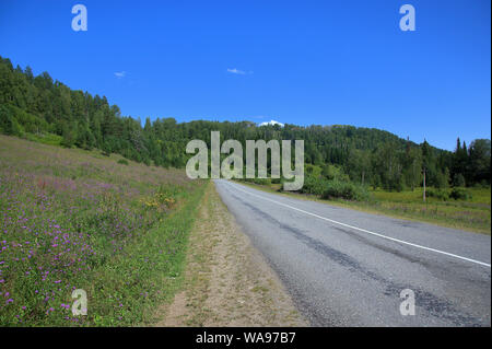 Strada asfaltata attraverso la valle circondata da catene montuose. Altai, Siberia, Russia. Foto Stock