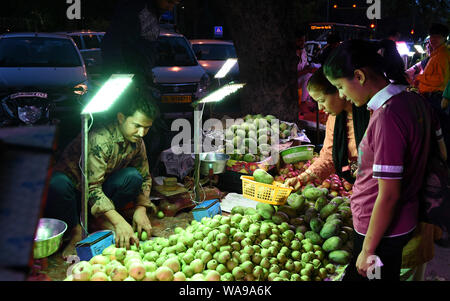 (190819) -- NEW DELHI, 19 Agosto, 2019 (Xinhua) -- persone selezionare di frutta sul mercato di domenica a Nuova Delhi, in India, e il agosto 18, 2019. Molti mercati di notte aperta nei fine settimana di New Delhi, attirando un numero di clienti per i prodotti freschi un prezzo inferiore. (Xinhua/Zhang Naijie) Foto Stock