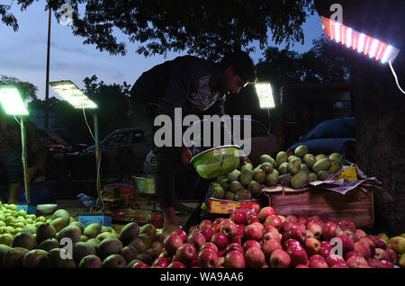 (190819) -- NEW DELHI, 19 Agosto, 2019 (Xinhua) -- Un uomo chiarisce i suoi beni sul mercato di domenica a Nuova Delhi, in India, e il agosto 18, 2019. Molti mercati di notte aperta nei fine settimana di New Delhi, attirando un numero di clienti per i prodotti freschi un prezzo inferiore. (Xinhua/Zhang Naijie) Foto Stock