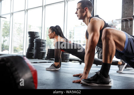 Un atleti muscolare facendo allenamento in palestra. Ginnastica, formazione fitness flessibilità. Attivo e uno stile di vita sano, gioventù, bodybuilding. Formazione in affondi e esercizi di stretching. Foto Stock