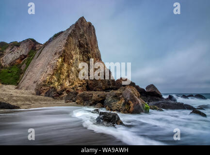 Torreggianti scogliere di Point Dume al tramonto di un giorno nuvoloso con onde che si infrangono in formazioni rocciose di seguito, Point Dume State Beach, Malibu, California Foto Stock